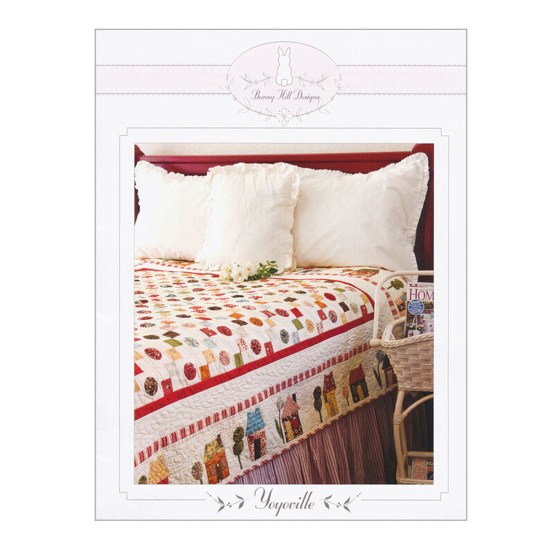 Front of yoyoville quilt pattern, showing the finished quilt on a bed with white pillows