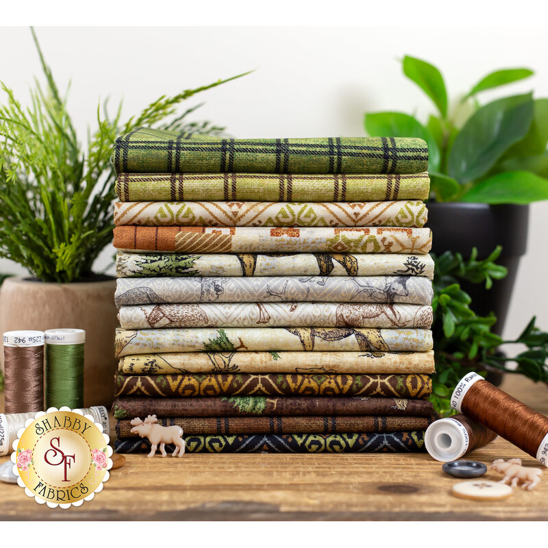 wildlife themed brown, cream, and green fabrics stacked on a table with plants, buttons, and thread