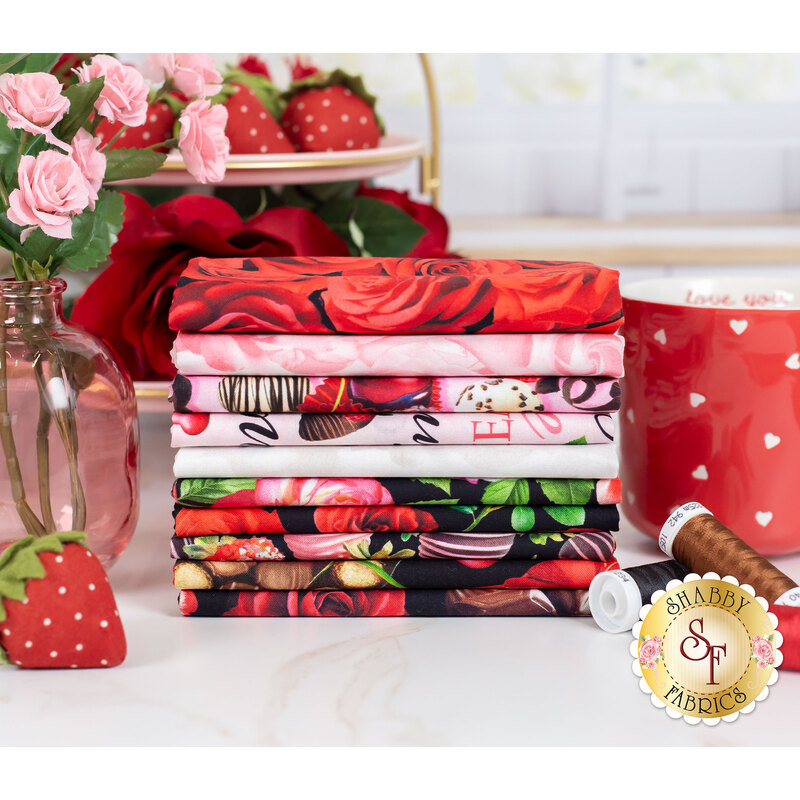 red, pink, and black fabric featuring chocolate covered cherries and strawberries, roses, and boxes of chocolates