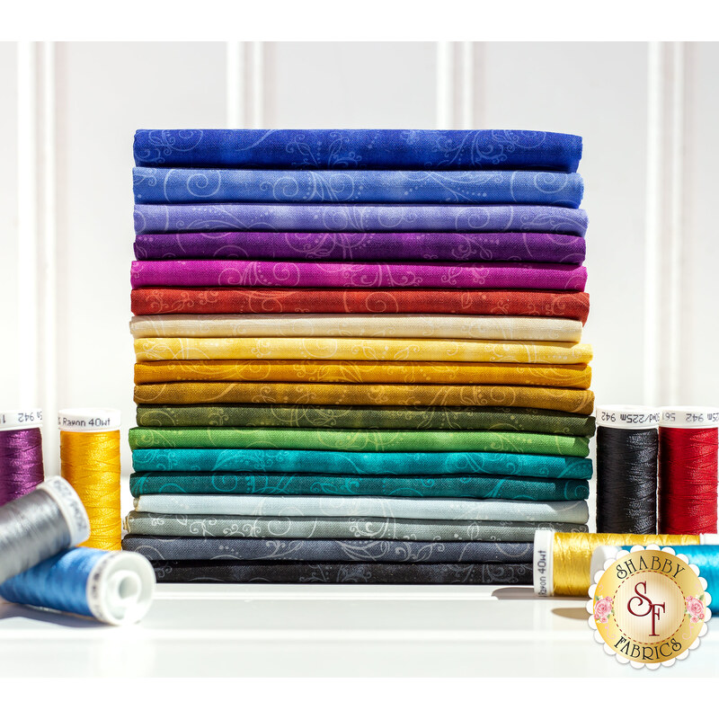 A collection of neatly stacked fabrics in various colors, including shades of blue, purple, yellow, green, and black, is displayed alongside spools of thread in coordinating colors.