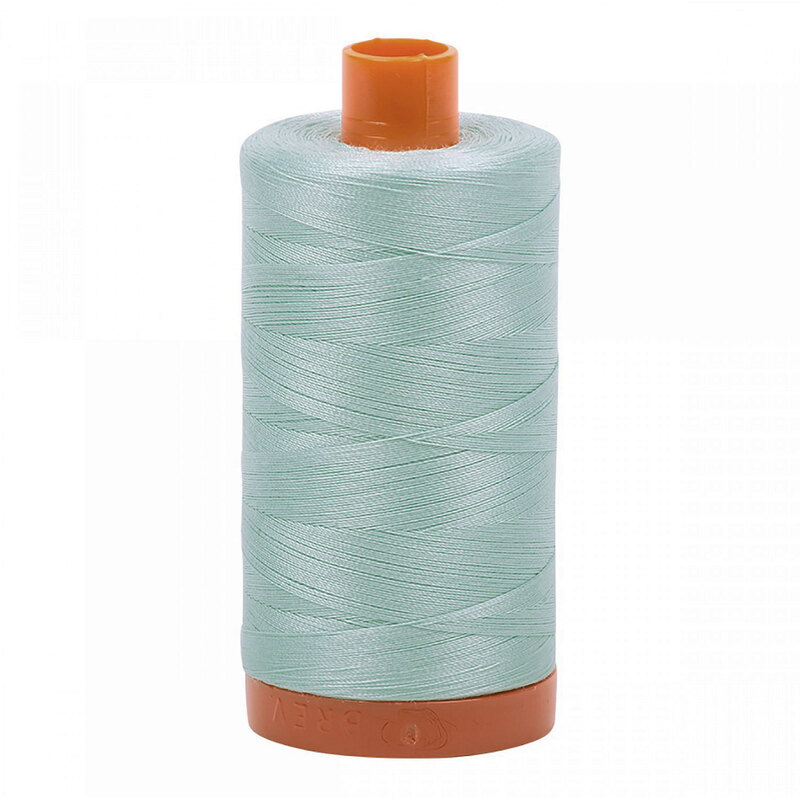 A spool of Aurifil 5007 - Light Grey Blue thread on a white background