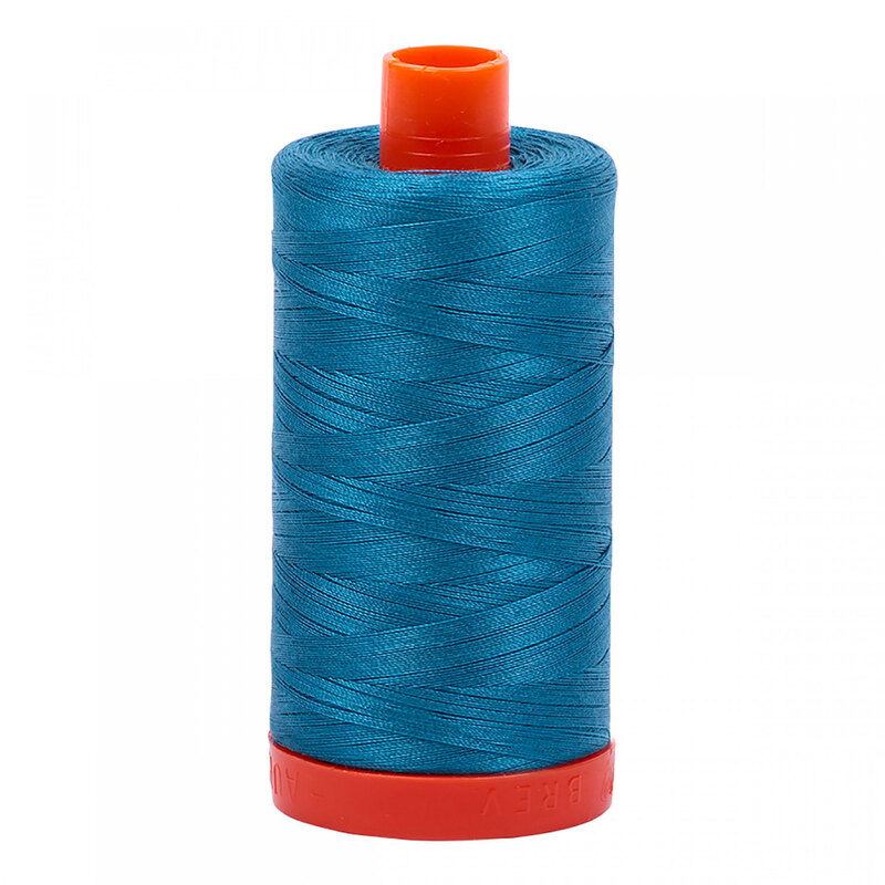 A spool of Aurifil 1125 - Medium Teal thread on a white background