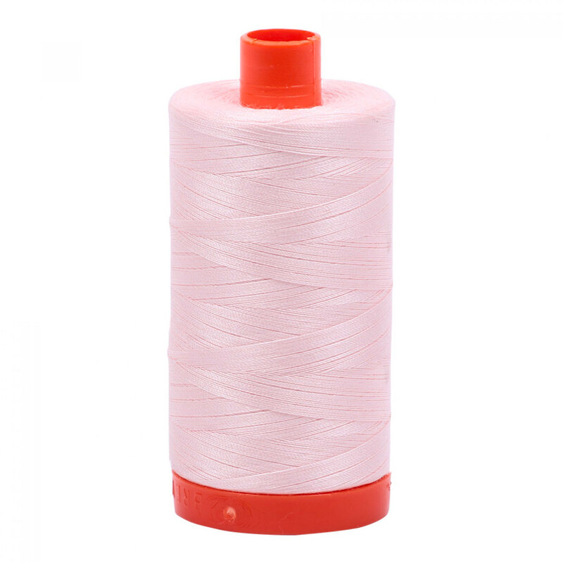 A spool of Aurifil 6723 - Fairy Floss thread on a white background