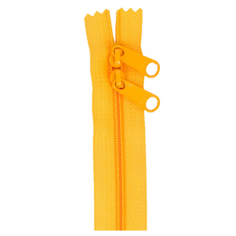 Close-up of a yellow zipper with two pulls and zigzagged tips, on a white background.