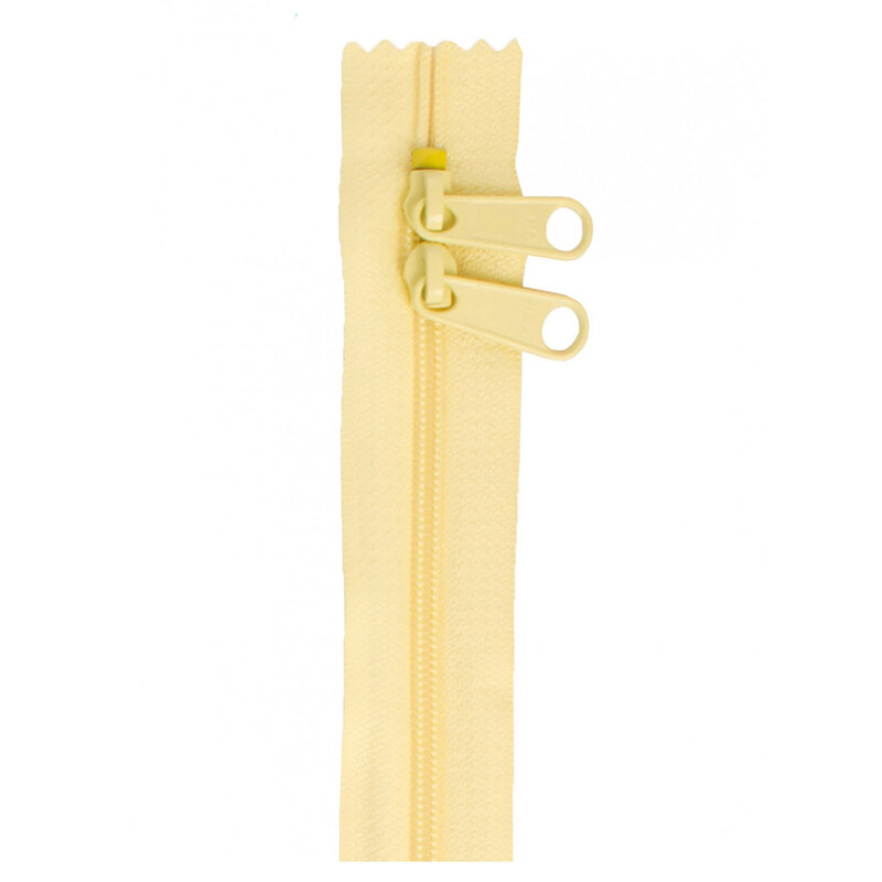 Photo of a yellow zipper with two pull tabs isolated on a white background