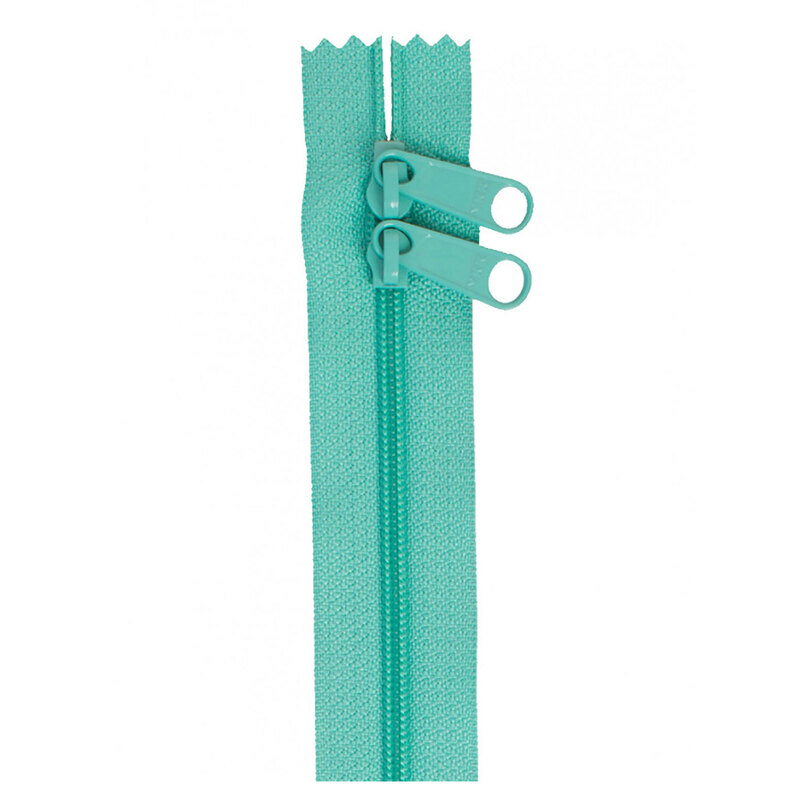 Photo of a teal zipper with two pull tabs isolated on a white background