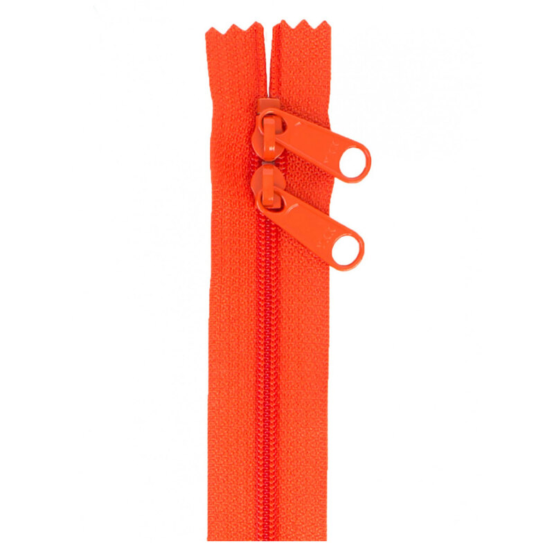 Photo of an orange zipper with two pull tabs isolated on a white background