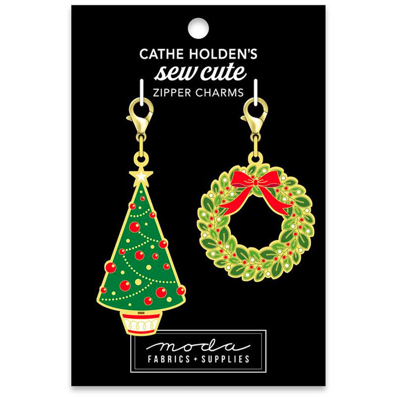 A card featuring two zipper charms: a green Christmas tree with red ornaments and a white base, and a green wreath decorated with a red bow. The background is black, and the card is labeled Cathe Holden's sew cute zipper charms.