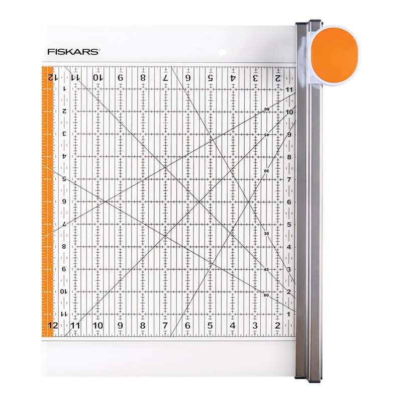 A Fiskars fabric cutter with a grid and measurement markings, featuring an orange rotary cutter handle.