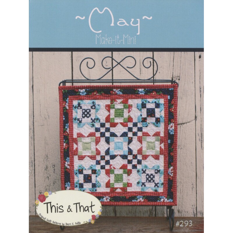 Front cover of pattern, showing the finished wallhanging hung from a craft scroll, staged in front of wood panels