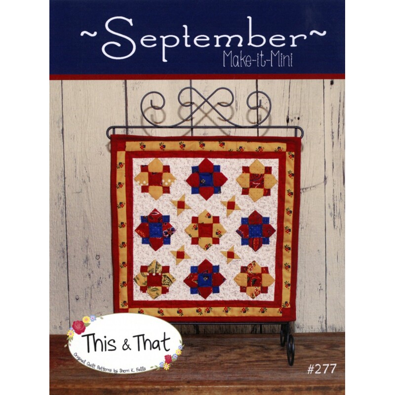 Front cover of pattern, showing the finished wallhanging hung from a craft scroll, staged in front of wood panels