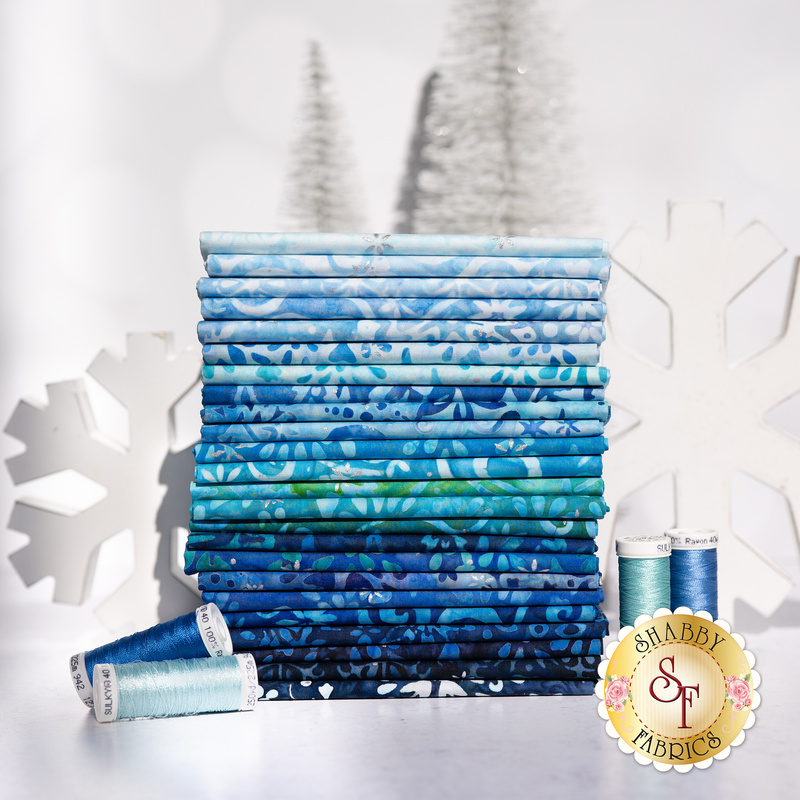 Stack of all Snowscape Batik fabrics, in gorgeous shades of blue, teal, and aqua with matching thread, set against a snowy background with decorative snowflakes.