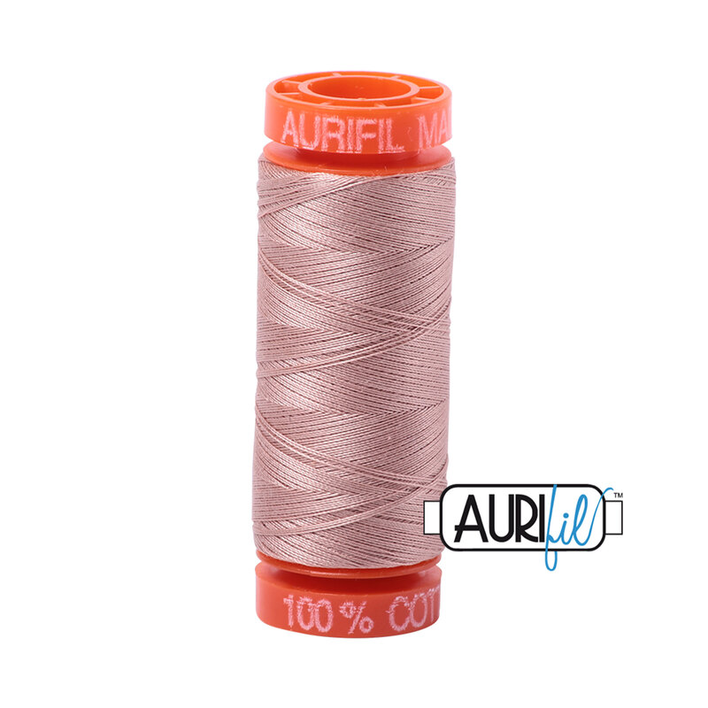 A spool of dusty pink Aurifil thread labeled 100% cotton, with an orange plastic top and base.