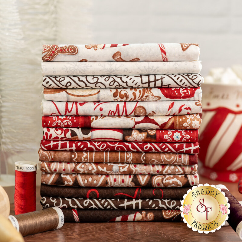 Stacked fabric bundles featuring patterns in red, white, and brown, with spools of thread nearby.