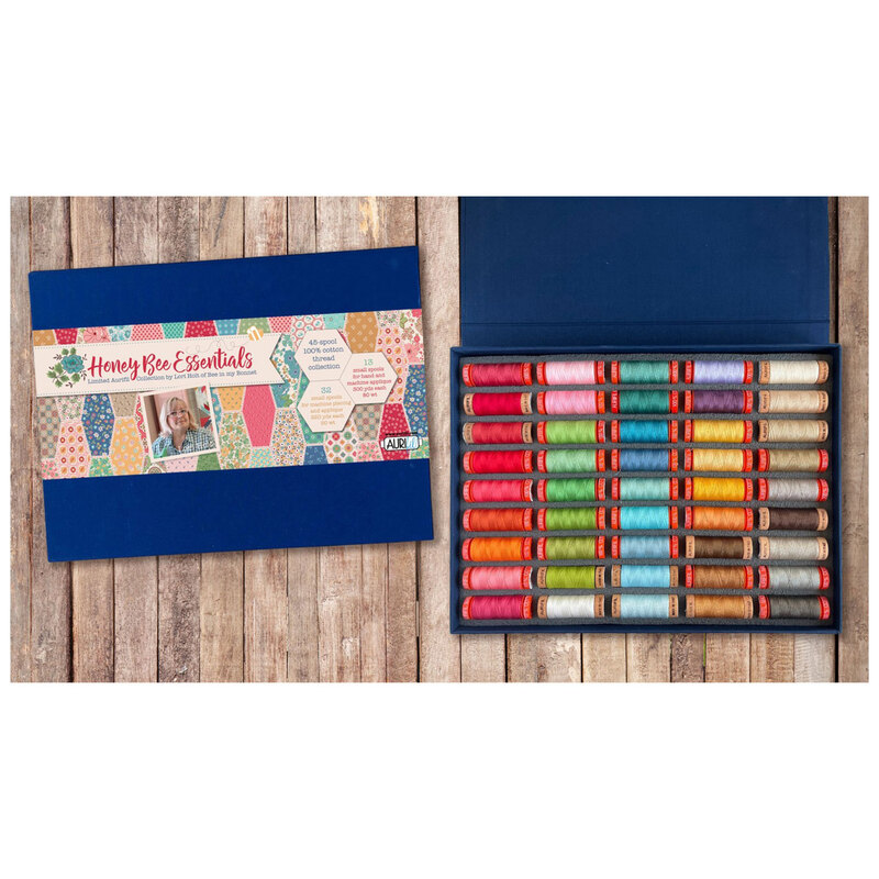 Image of the thread set from above, showing the thread spools arranged in rainbow order, staged atop rustic wood. 