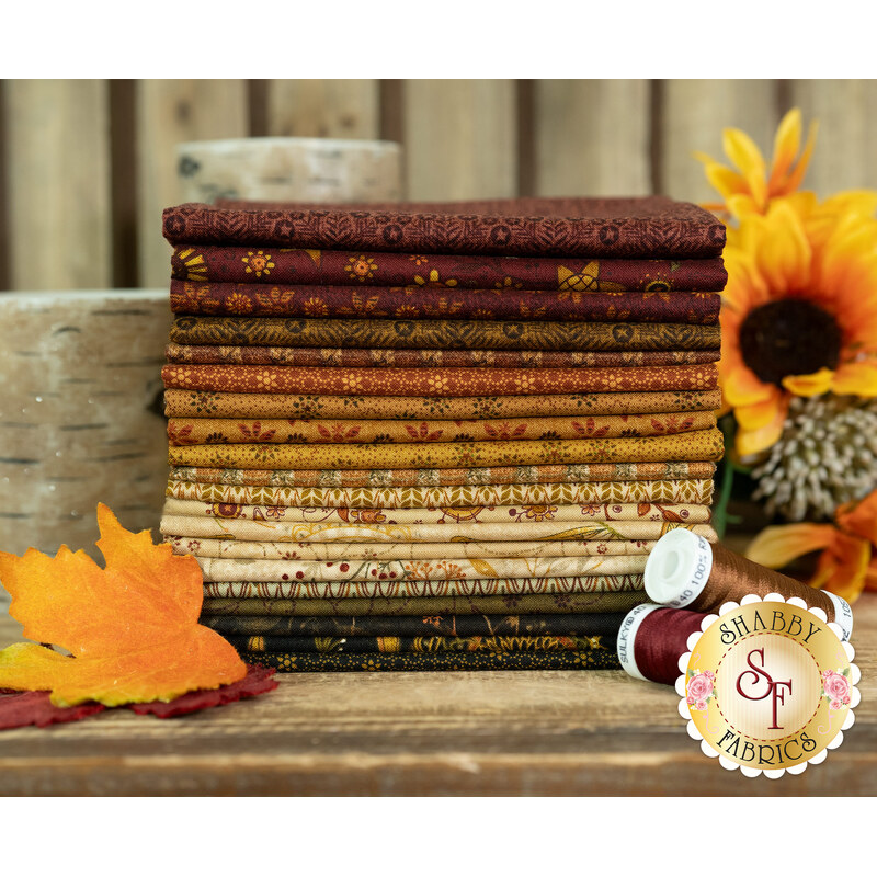 A stack of fabrics in Oak and Maple FQ set with flowers and candles and leaves and thread.