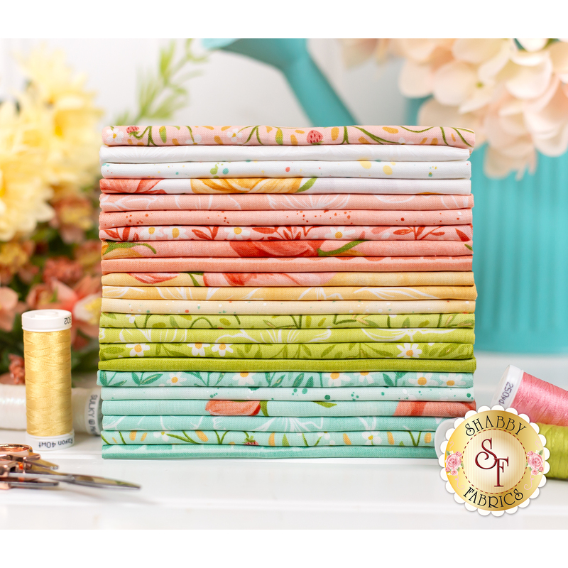 pink, yellow, green, blue, and white fabric on a white table surrounded by matching thread and flowers