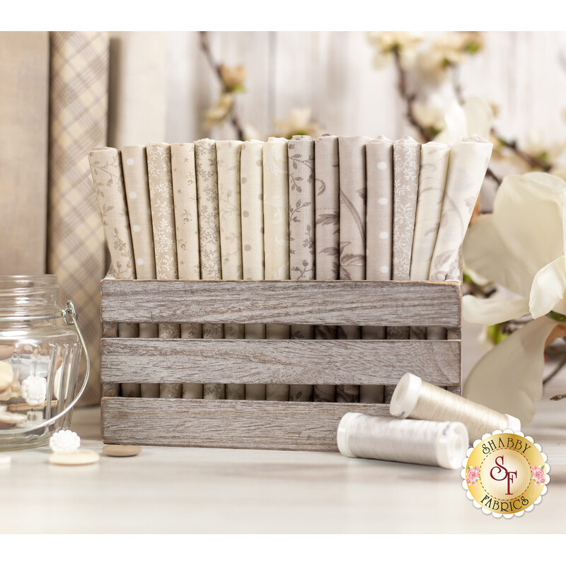 floral fabrics in lovely shades of cream and beige, stacked in a wood basket