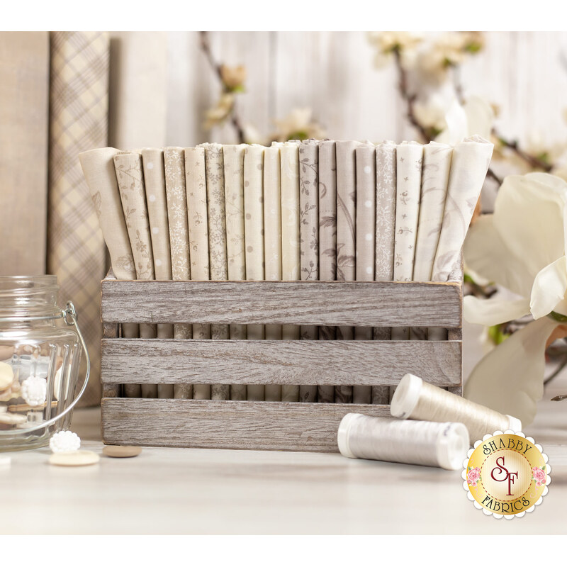 floral fabrics in lovely shades of cream and beige, stacked in a wood basket