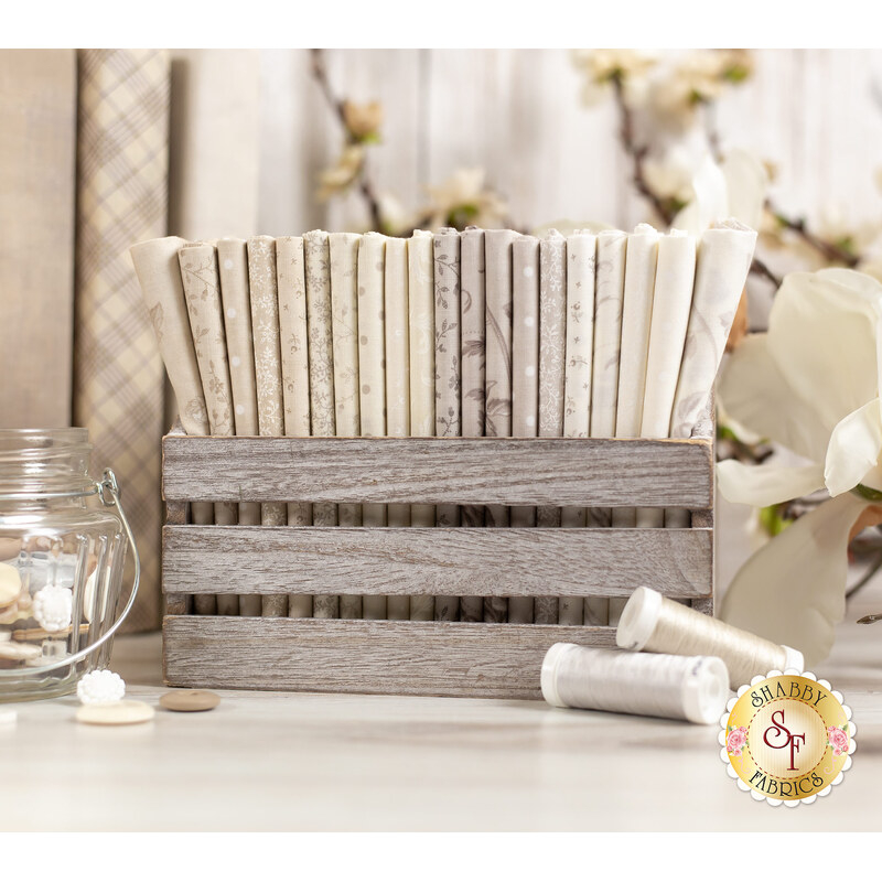 floral fabrics in lovely shades of cream and beige, stacked in a wood basket