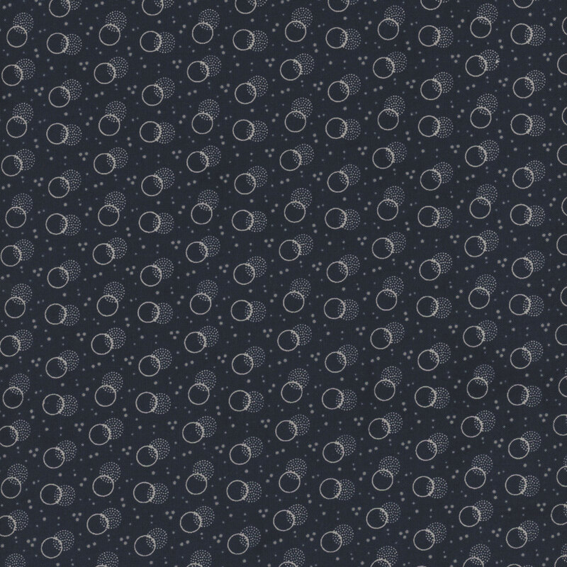 navy blue fabric with light blue speckling and layered off white circles and stippled polka dots