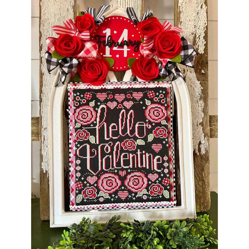 cross stitch design showing the completed project featuring the phrase "hello valentine" with hearts and roses