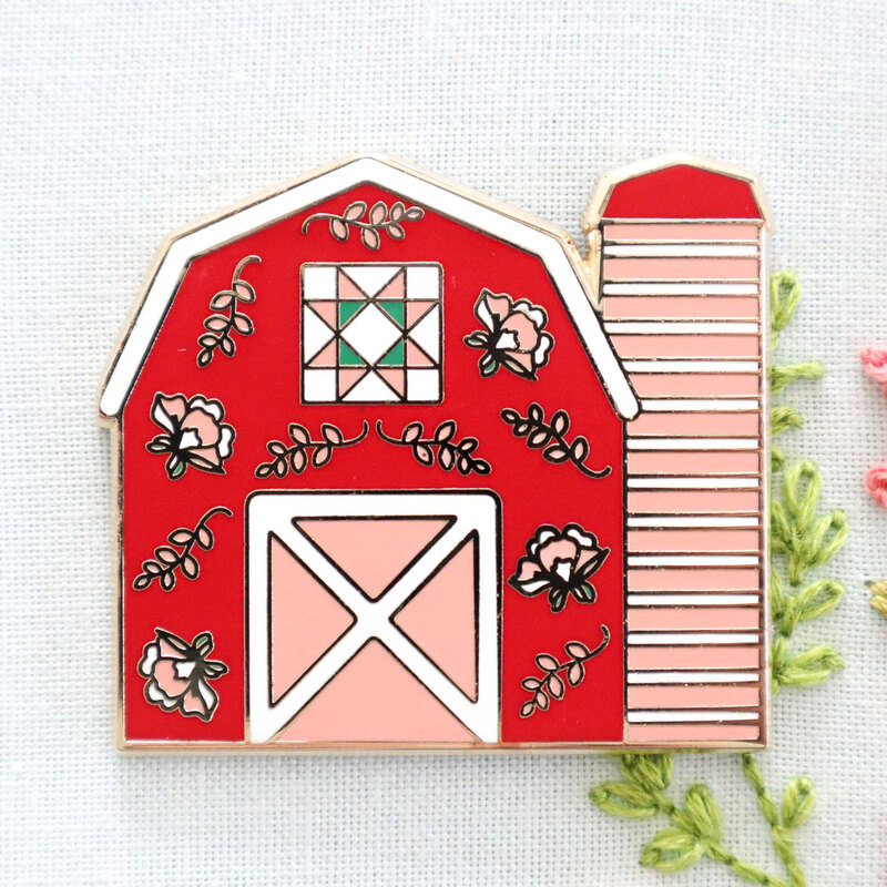 A barn shaped magnetic needle minder displayed on a hand embroidery project 