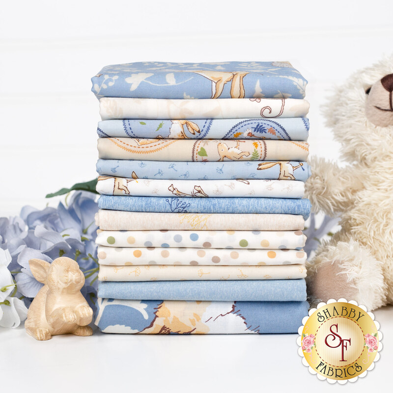 A stack of fabrics included in the Guess How Much I Love You 2024 collection, with flowers, a teddy bear, and a bunny statue.