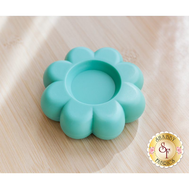 Light blue magnetic dish shaped like a flower, resting on a wooden surface.