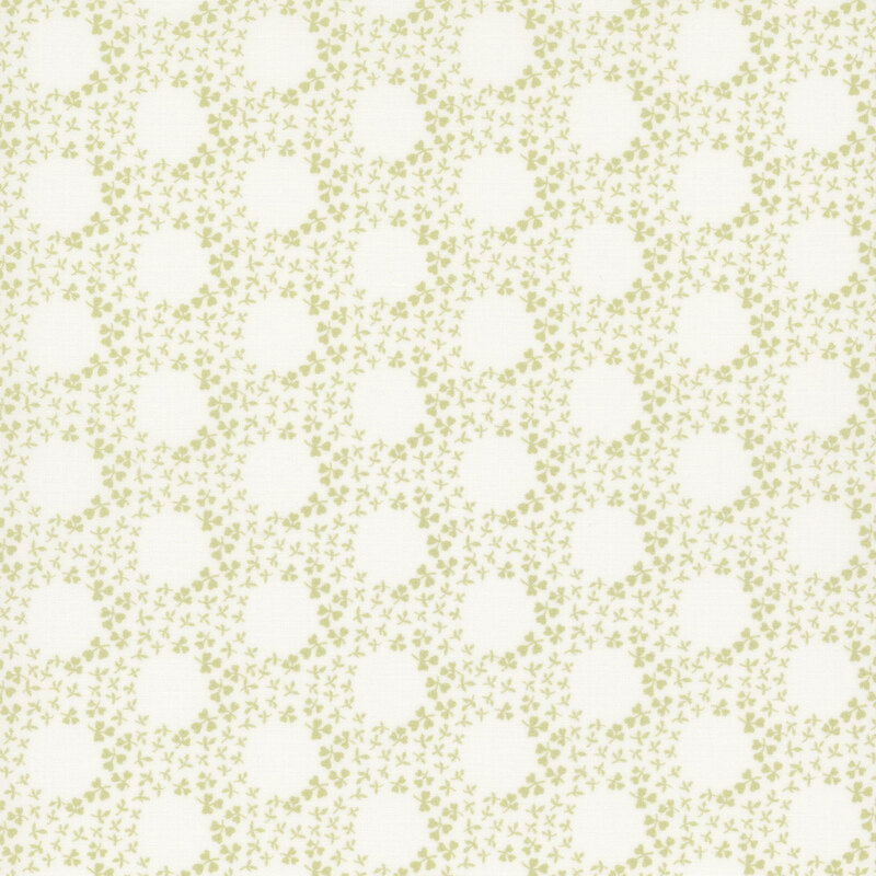 A white fabric with small green clovers forming rings.