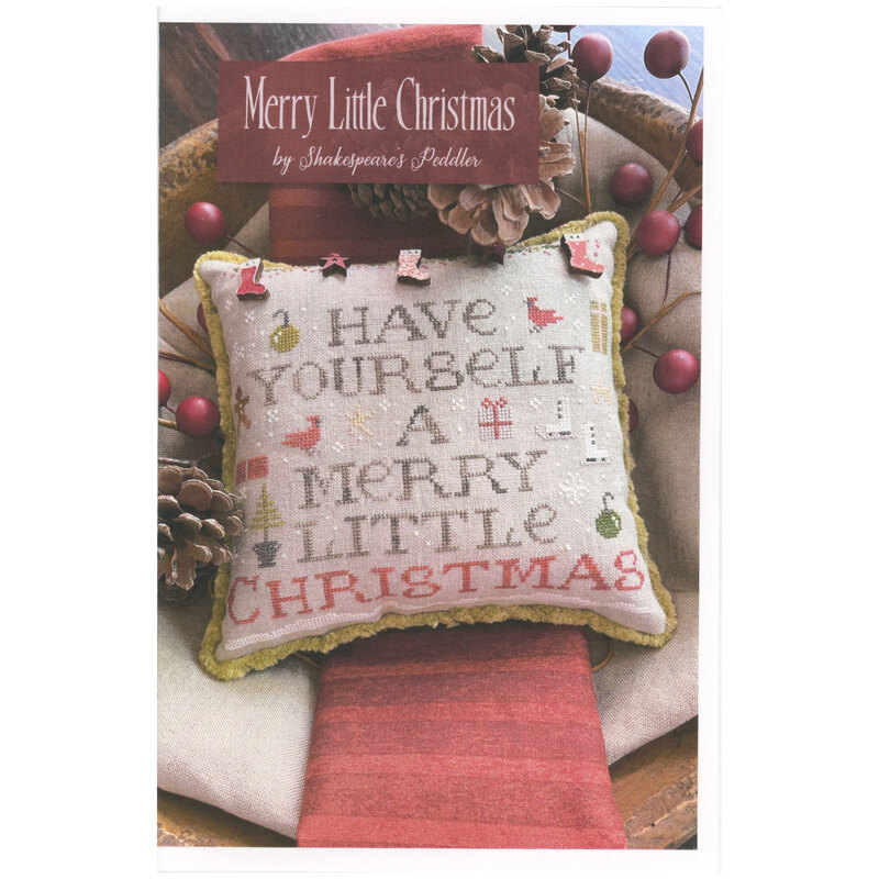 Front of pattern showing the completed cross stitch on a pillow staged in a bowl with pinecones and berries