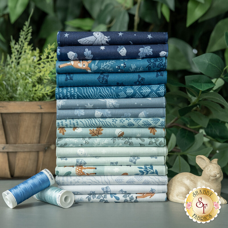 A stack of the fabrics included in the Twilight Creatures FQ Set, with greenery and thread and a bunny figurine.