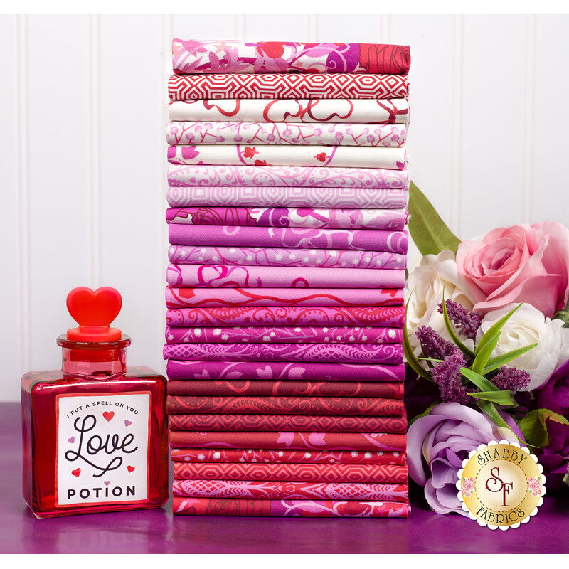 A photo of a stack of pink, red and white fabrics in the Heart Nouveau FQ set