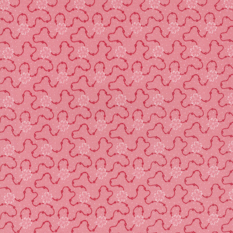 Pink fabric featuring a swirly dotted design with white flowers and scattered white dots