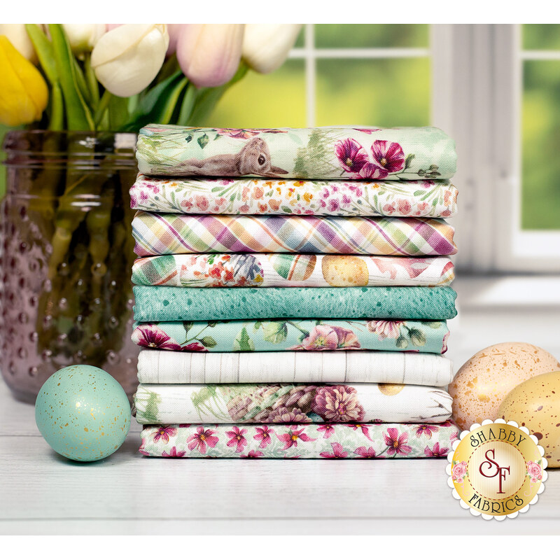 A stack of the Easter Wishes FQ set featuring bunnies, easter eggs and florals in cream, light green and turquoise, with flowers in a vase and eggs.