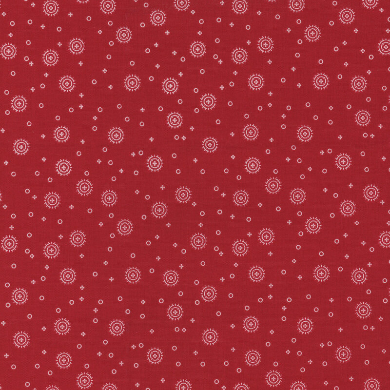 red fabric with tiny white circles and four-petaled flowers with larger circular sunbursts scattered across the fabric