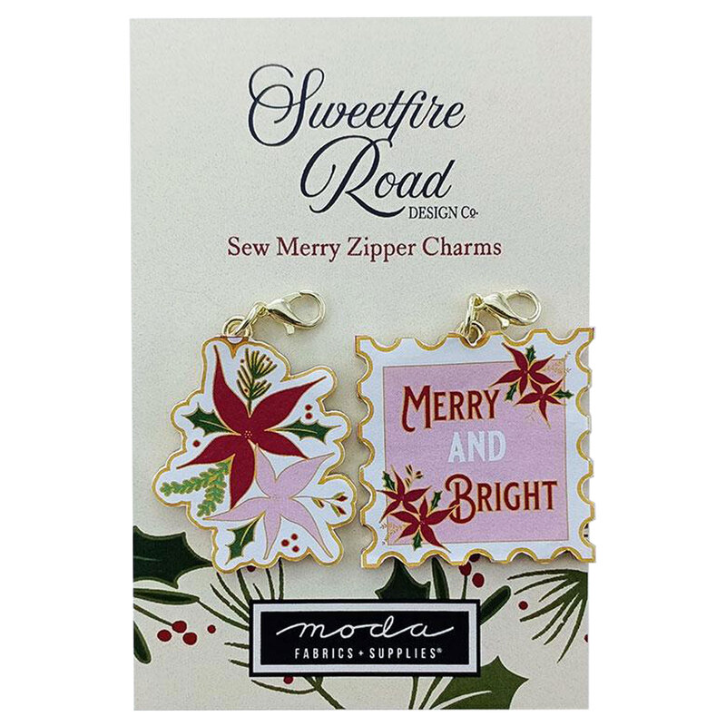 A package of two zipper charms featuring a floral design and the text Merry and Bright on a pink background, surrounded by decorative borders. The package is labeled with Sweetfire Road Design Co and Moda Fabrics & Supplies.