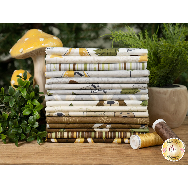 A stack of fabrics from the Into the Woodlands collection, with plants and mushrooms and thread.