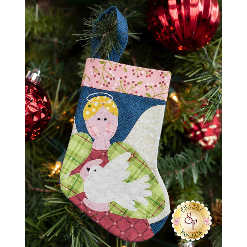 The completed Angel stocking, hung on a green Christmas tree decorated with red bulbs.