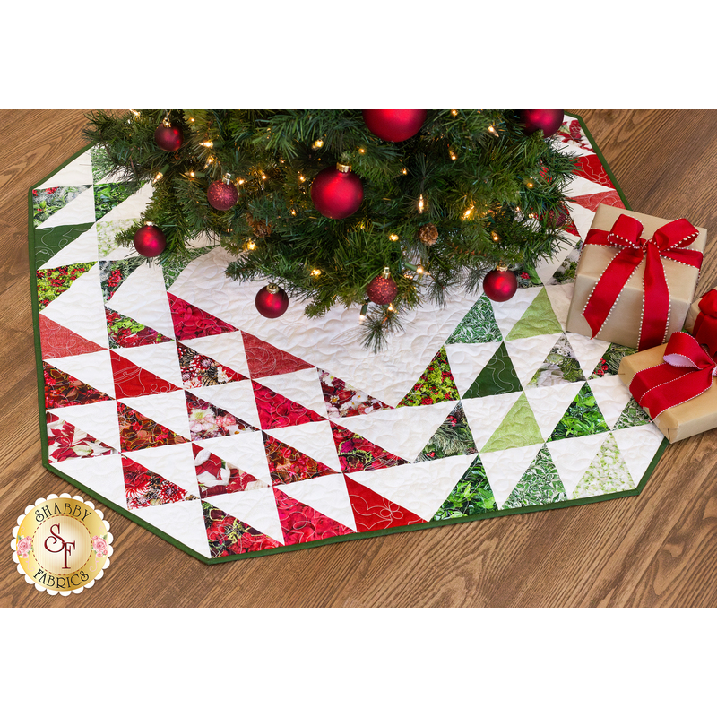 The finished tree skirt in a pleasing array of red and green displayed underneath a decorated Christmas tree with coordinating gift decor placed underneath the tree.