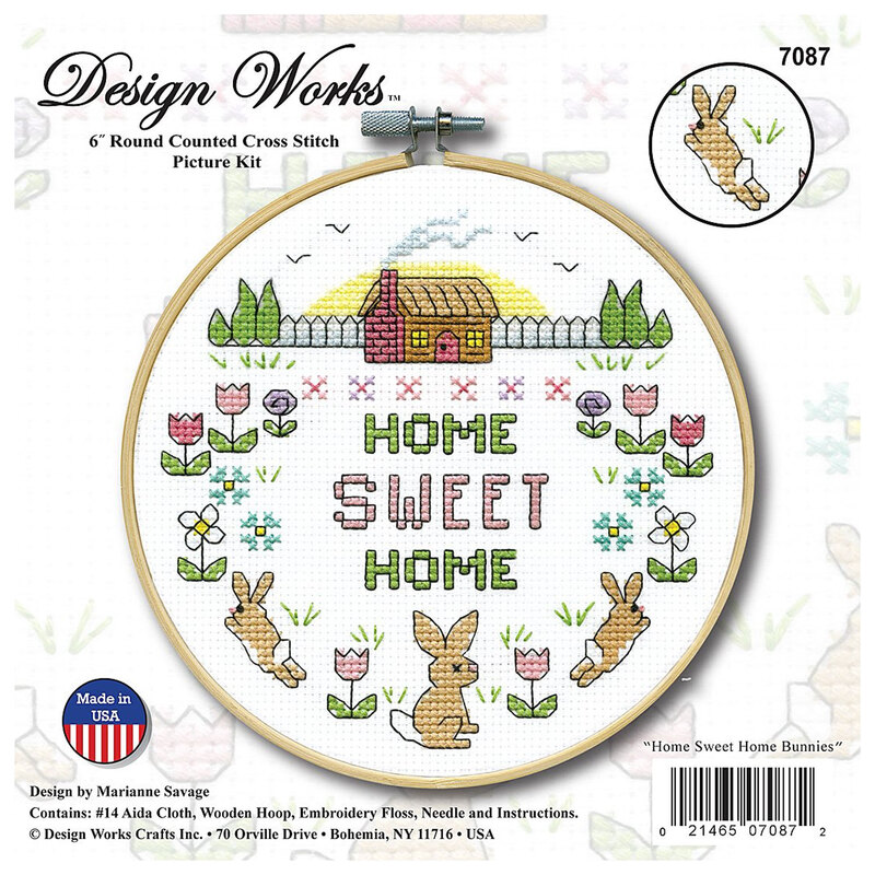 The front of the cross stitch kit featuring a picture of the finished cross stitch with bunnies running in a spring field in a wooden hoop.