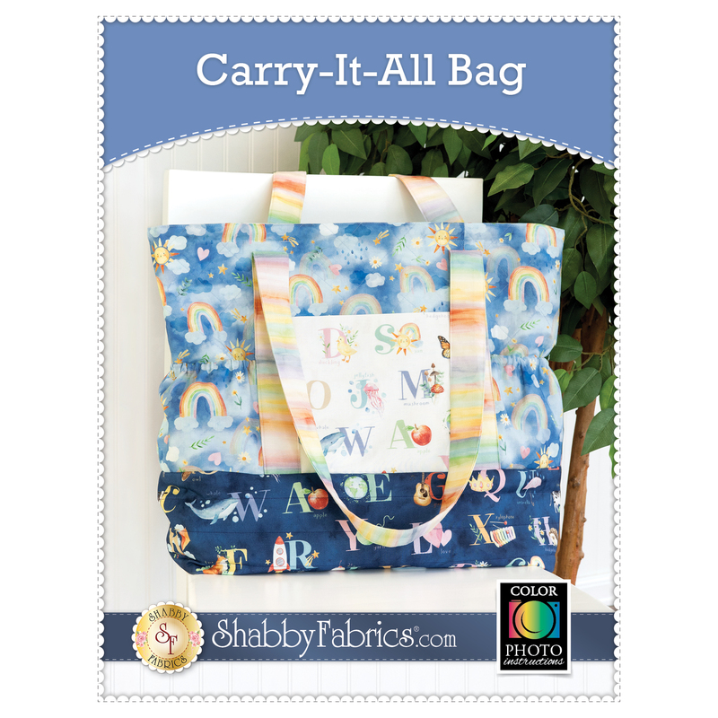 Front cover of the Carry-It-All Bag showing the completed bag, colored in blue, navy, and rainbow prints from the Love and Learning collection, staged on a white chair with a leafy houseplant.