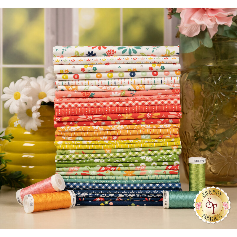 A stack of a colorful fabric bundle with floral patterns, spools of thread, and decorative flowers.