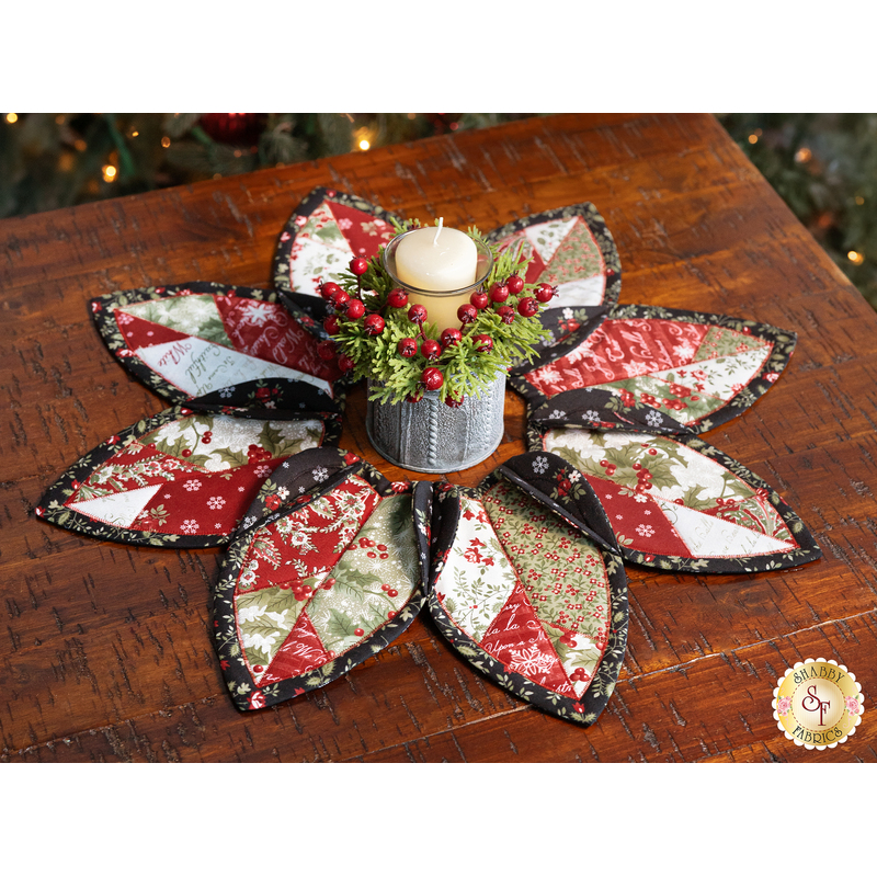 The completed Fold'n Stitch Leaf Topper, staged on a rustic wood table with coordinating decor in the center. A lit Christmas tree peeks into frame from the top of the photo.