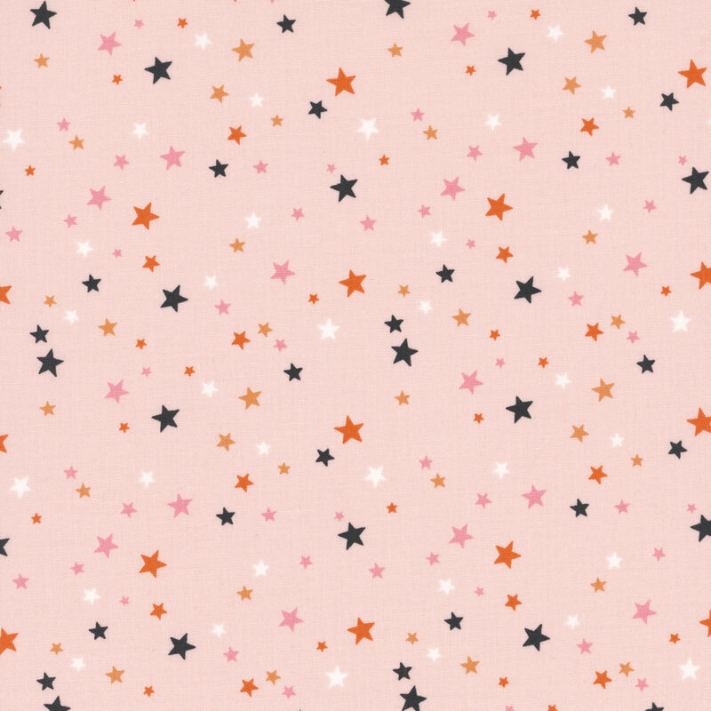 Blush pink fabric with scattered stars in Halloween colors and pink.