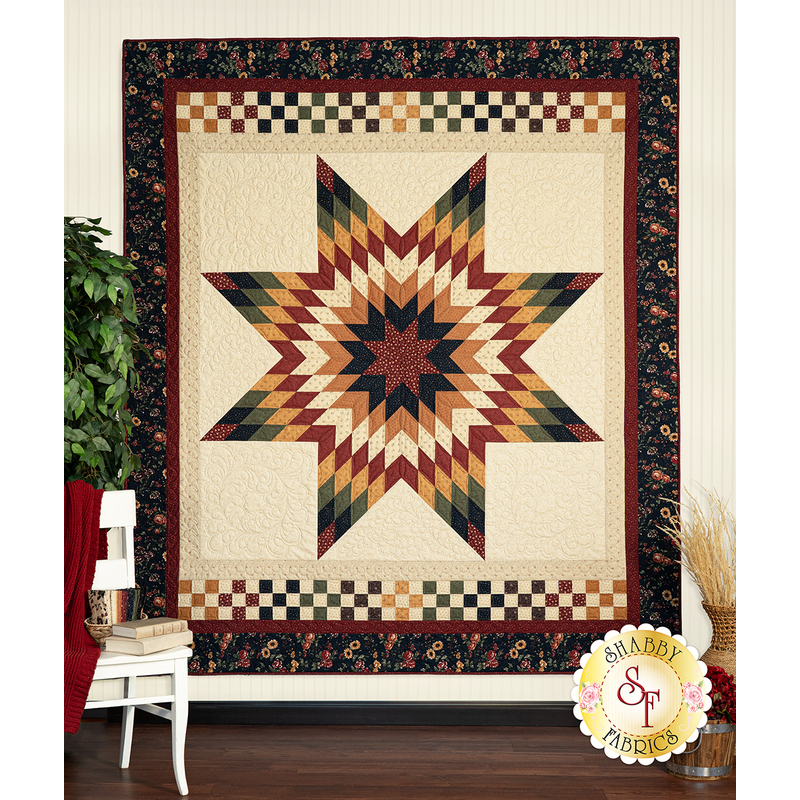 A colorful quilt featuring a star design with rich reds, yellows, and greens, displayed on a wall.