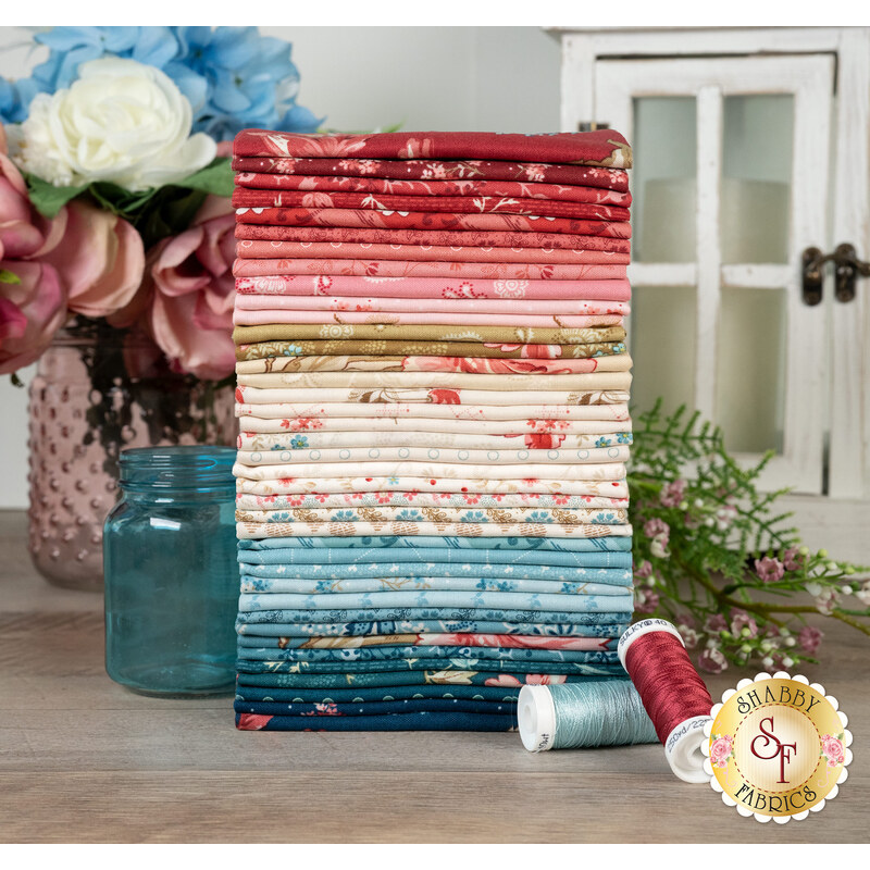 A stack of the fabrics featured in the Lighthouse fabric collection, with a lantern, flowers, jars, and thread.