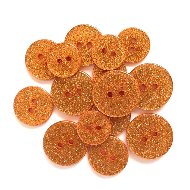 Pile of orange glitter buttons against a white background