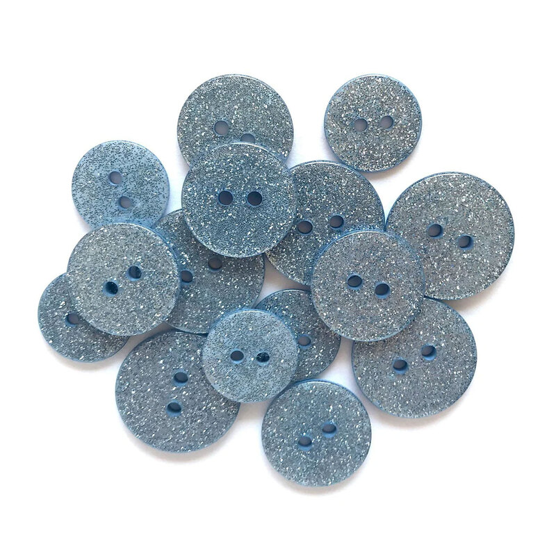 Pile of light blue glitter buttons against a white background