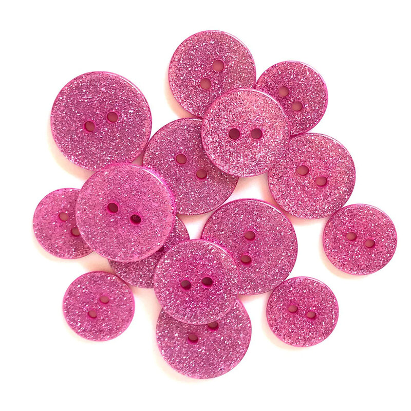 Pile of pink glitter buttons against a white background